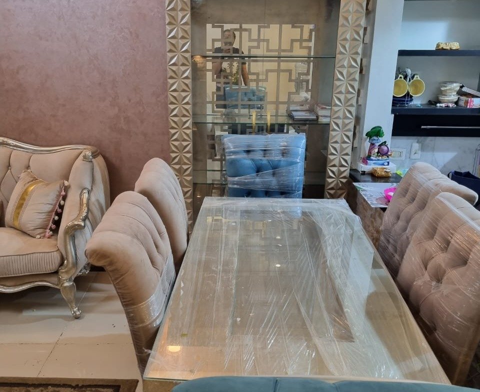 Dining table with upholstered chairs beside a stone fireplace wall - duplex in Porto, New Cairo