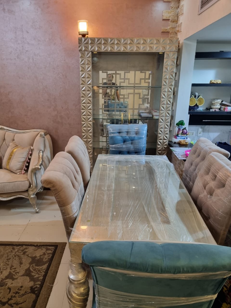 Dining table with upholstered chairs beside a stone fireplace wall - duplex in Porto, New Cairo