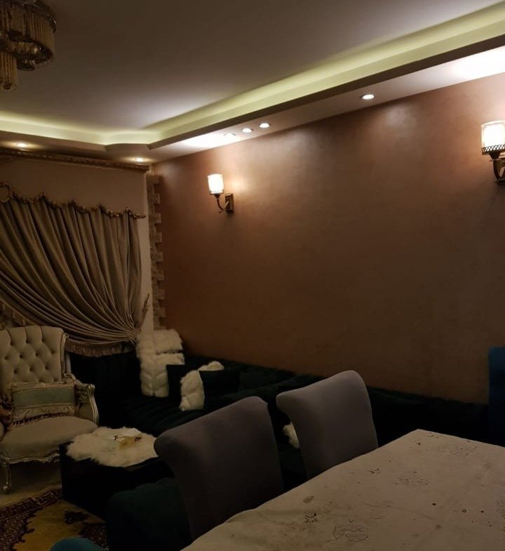 Dim bedroom corner with a dark bed and warm lamps - duplex in Porto, New Cairo