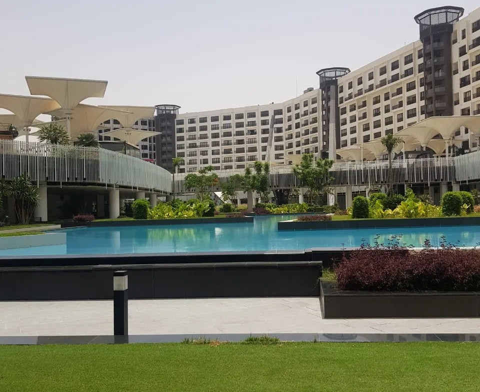 Large pool and lawn in front of a hotel-style building - duplex in Porto, New Cairo