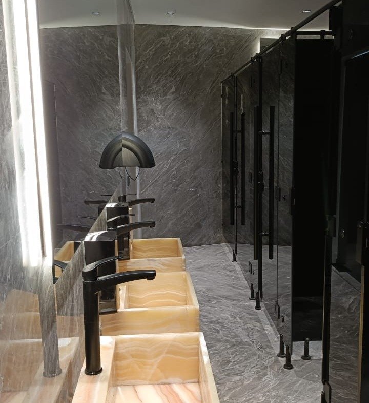 Restroom with a row of vessel basins on a lit stone counter - unit in Marassi