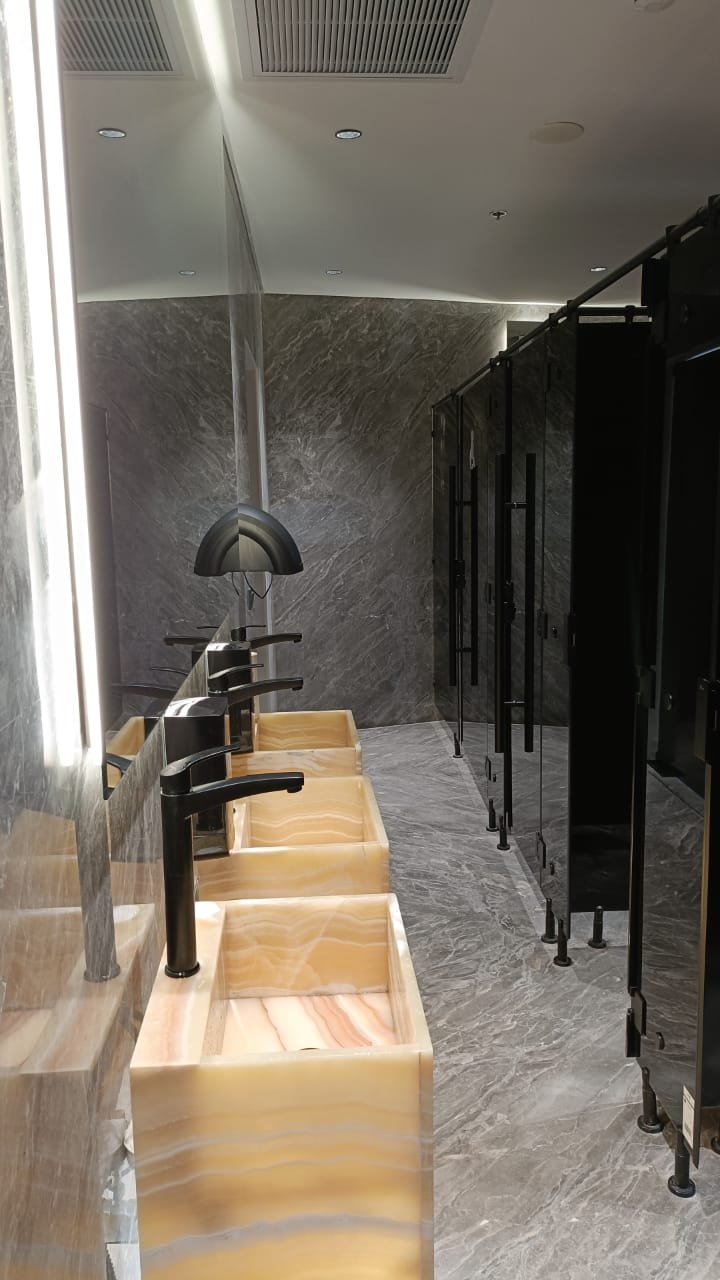 Restroom with a row of vessel basins on a lit stone counter - unit in Marassi