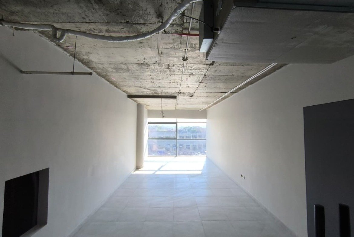 Narrow bare shell unit with an exposed concrete ceiling and a window at the end - unit in Marassi