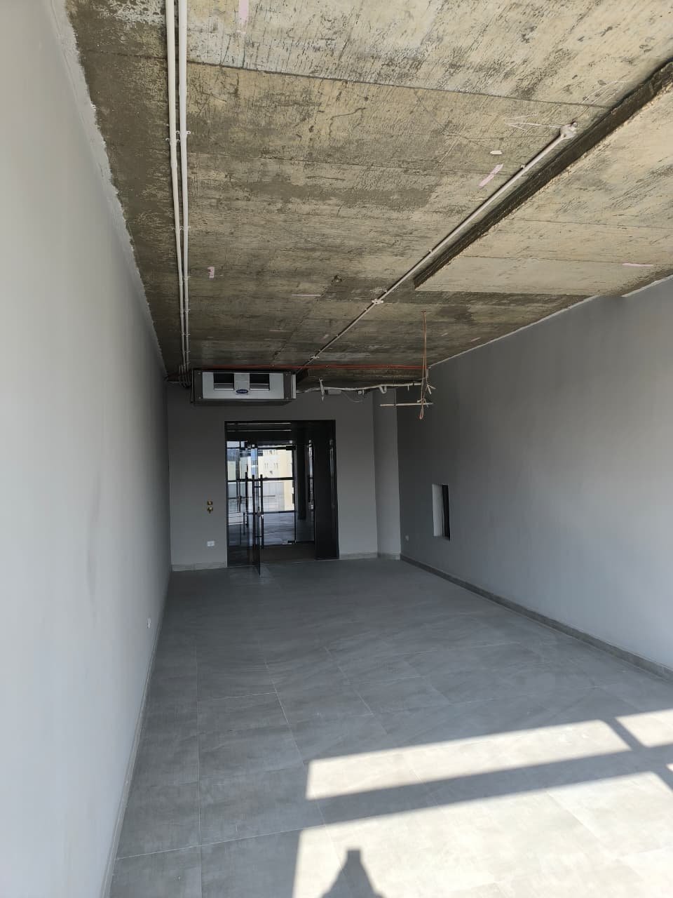 Long shell space with sunlight patches on the floor and a concrete ceiling - unit in Marassi
