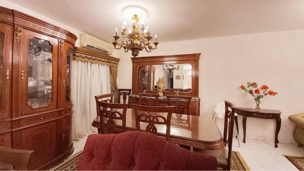 Wooden dining set and a glass cabinet under a chandelier - apartment in El Rehab New Cairo – 3 Bedrooms 183 sqm – Garden View, New Cairo