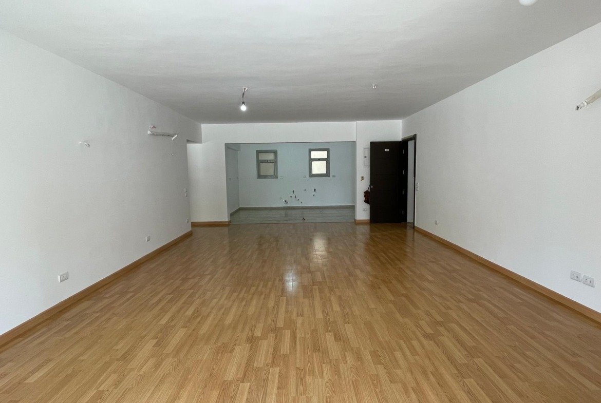 Long empty reception with a laminate floor and white walls - apartment in Capital Gardens Next to Madinaty, Mostaqbal City