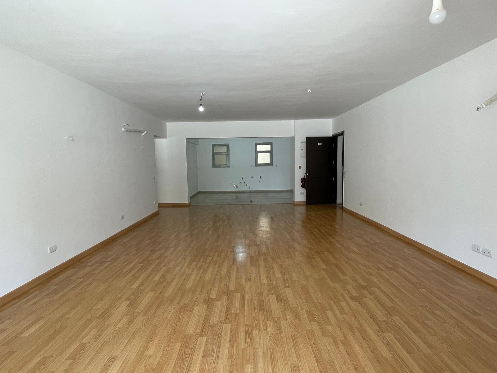 Long empty reception with a laminate floor and white walls - apartment in Capital Gardens Next to Madinaty, Mostaqbal City