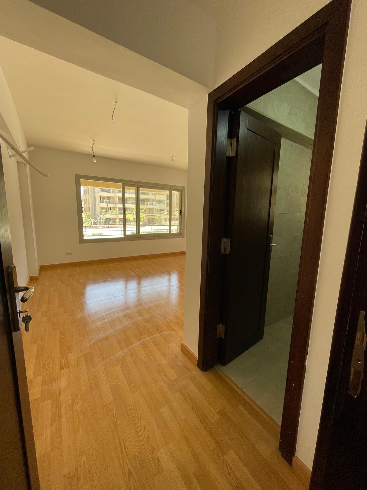 Doorway into a room with a window and a wooden floor - apartment in Capital Gardens Next to Madinaty, Mostaqbal City