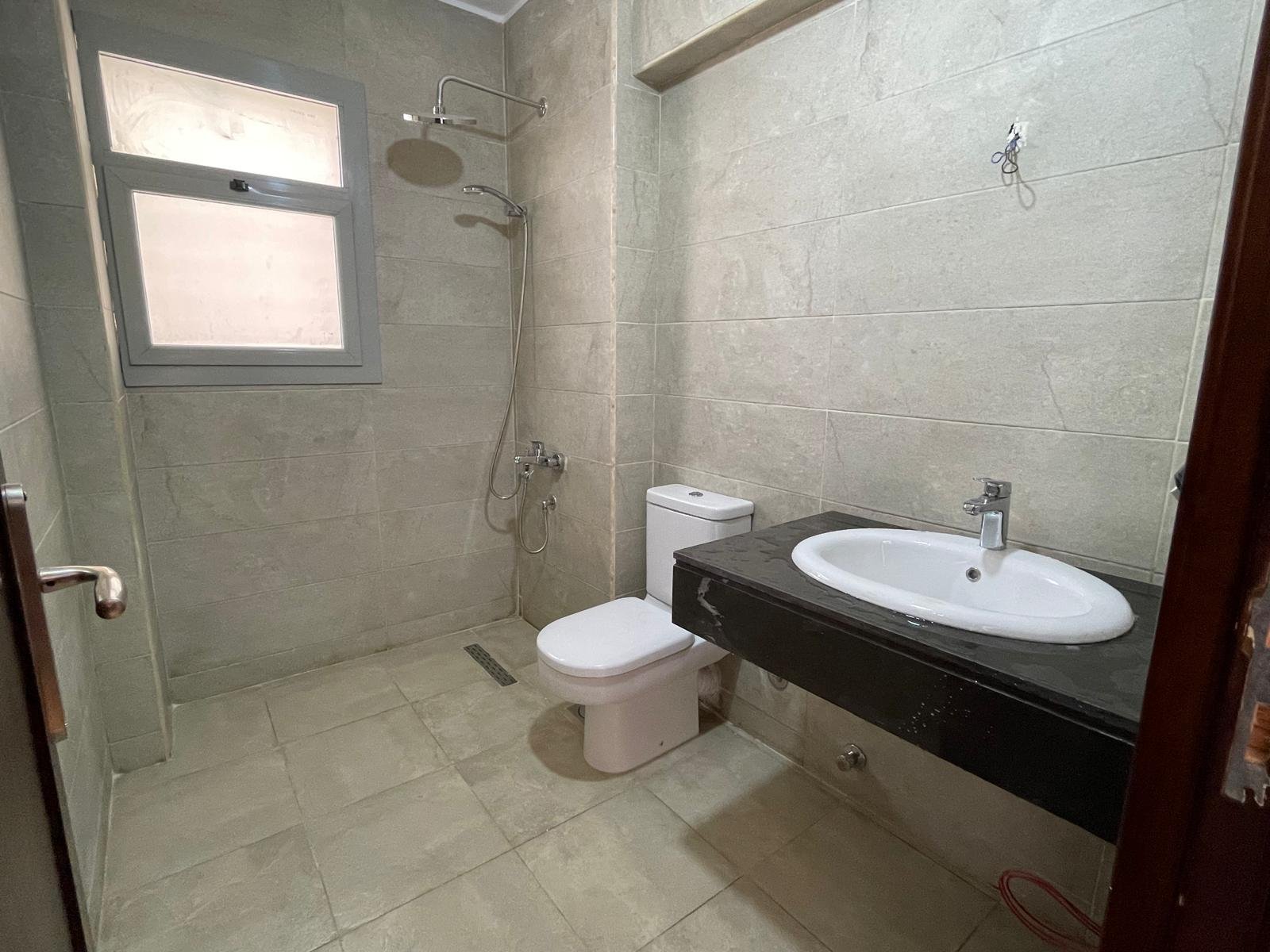 Bathroom with a black counter, a white basin and a shower - apartment in Capital Gardens Next to Madinaty, Mostaqbal City
