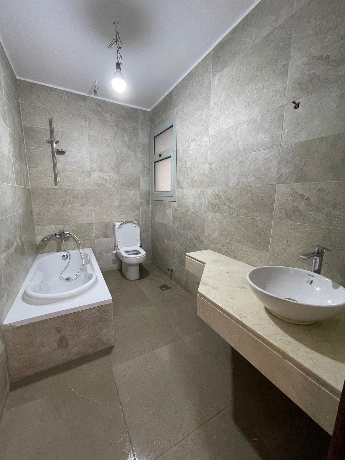 Bathroom with a round basin, a bathtub and grey wall tiles - apartment in Capital Gardens Next to Madinaty, Mostaqbal City