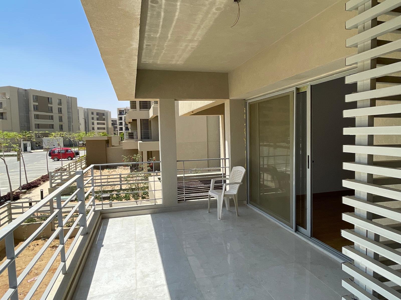 Balcony with a metal railing, timber slats and a sliding glass door - apartment in Capital Gardens Next to Madinaty, Mostaqbal City
