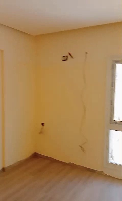 Empty room with warm yellow walls and wood floor - apartment in Mountain View iCity, New Cairo