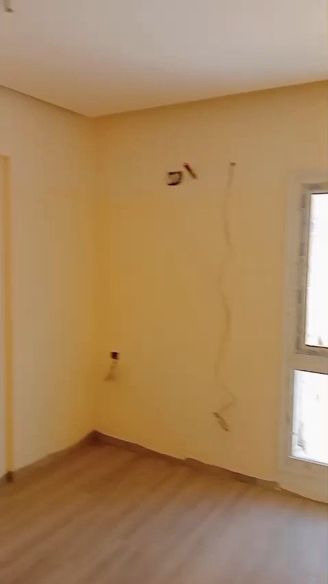 Empty room with warm yellow walls and wood floor - apartment in Mountain View iCity, New Cairo
