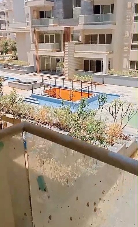 Balcony glass railing overlooking a pool and apartment buildings - apartment in Mountain View iCity, New Cairo