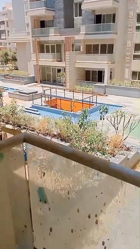 Balcony glass railing overlooking a pool and apartment buildings - apartment in Mountain View iCity, New Cairo
