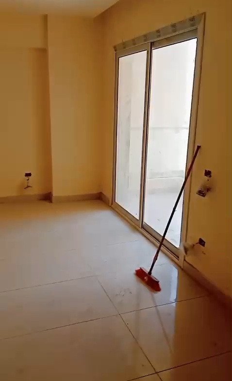Empty room with a sliding glass door and a mop leaning on the wall - apartment in Mountain View iCity, New Cairo