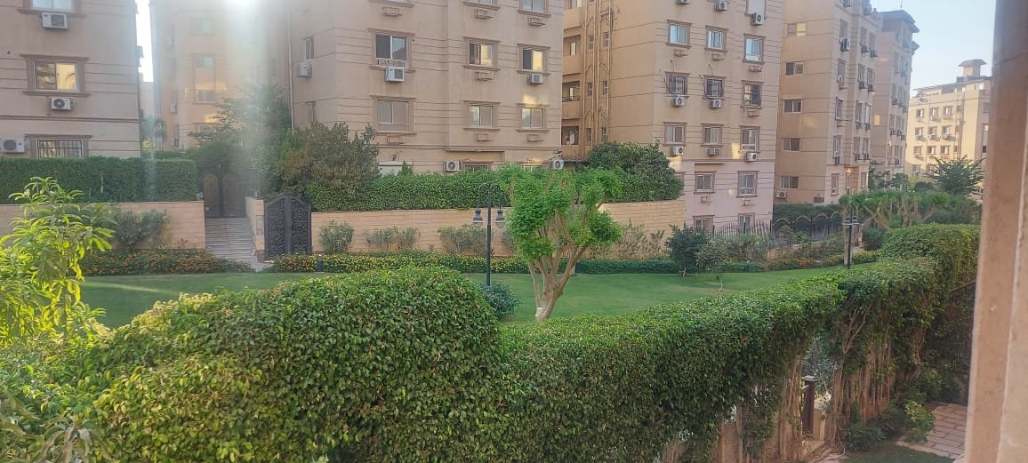 سور شجر ونجيل أمام العمارات من الشباك - شقة في فاميلي سيتي، التجمع الخامس