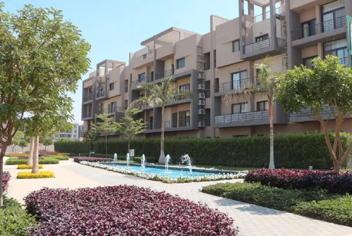 Fountain and flower beds beside apartment buildings - apartment in Fifth Square, New Cairo