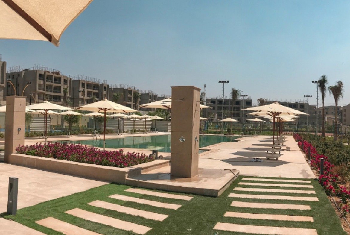 Pool area with umbrellas and flower beds - apartment in Fifth Square, New Cairo