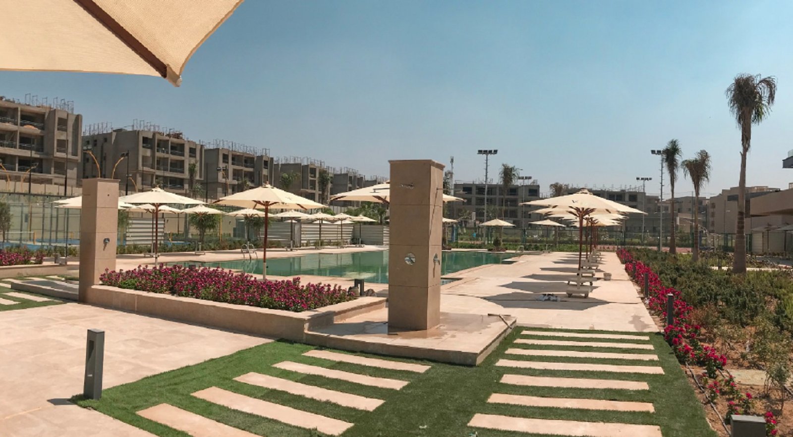 Pool area with umbrellas and flower beds - apartment in Fifth Square, New Cairo