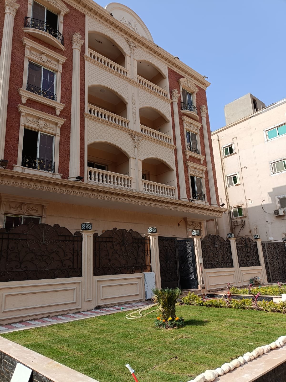 Pink-stone apartment building with a lawn in front - apartment in Gharb Arabella, 5th Settlement