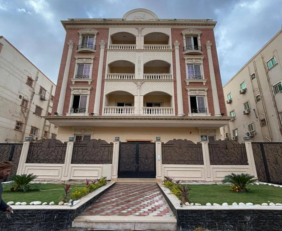 Front of a four-floor apartment building with a central stair path - apartment in Gharb Arabella, 5th Settlement