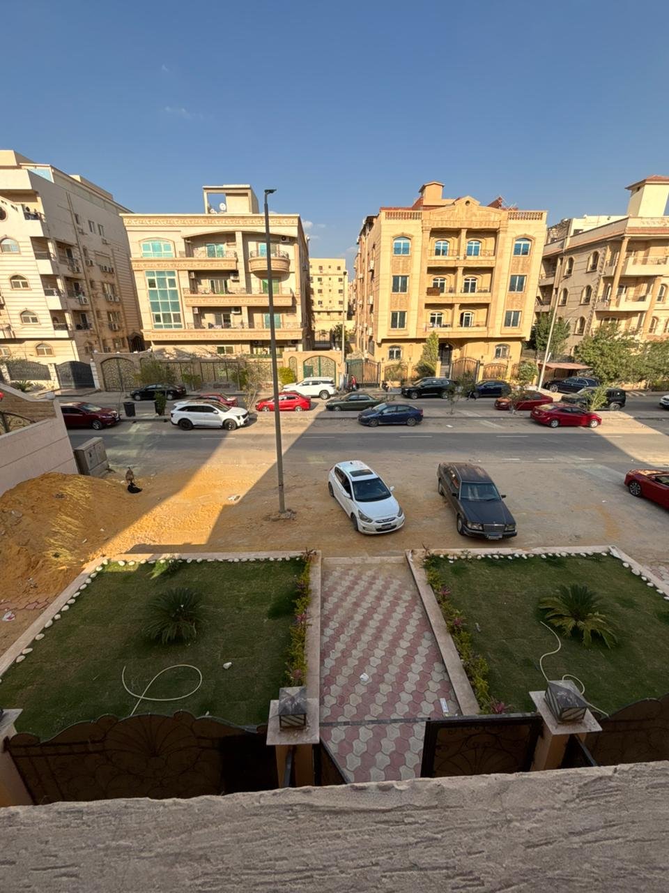 View over a parking court and garden beds between residential buildings - apartment in Gharb Arabella, 5th Settlement