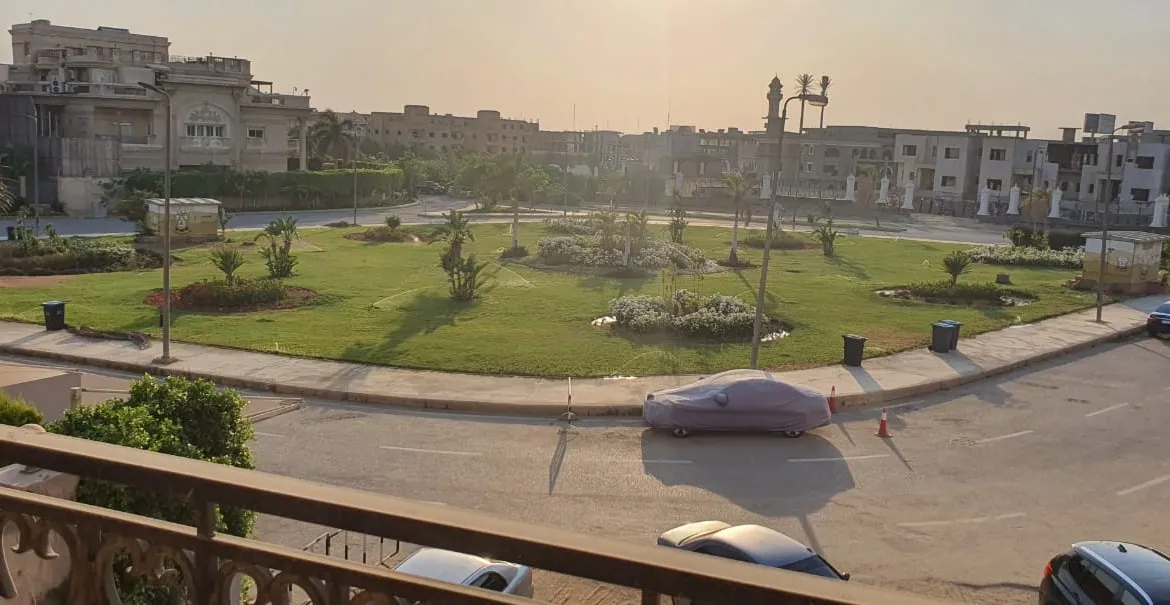 Balcony view over a lawn and a curving street in the compound - apartment in Gharb Golf 5th Settlement