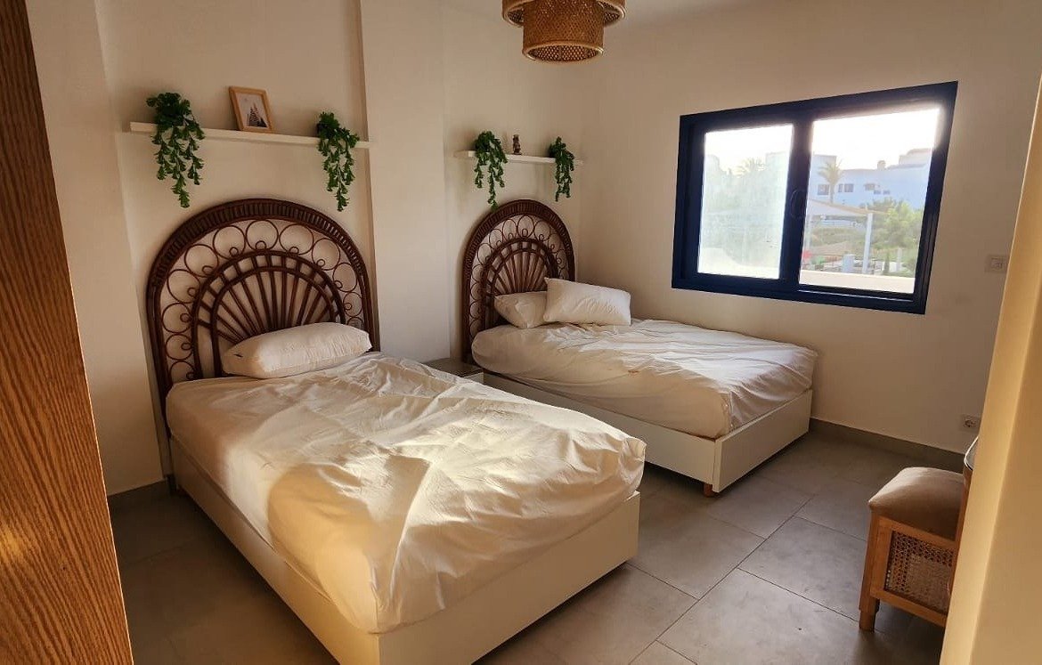 Twin bedroom with rattan headboards and plants - townhouse in Marassi, North Coast