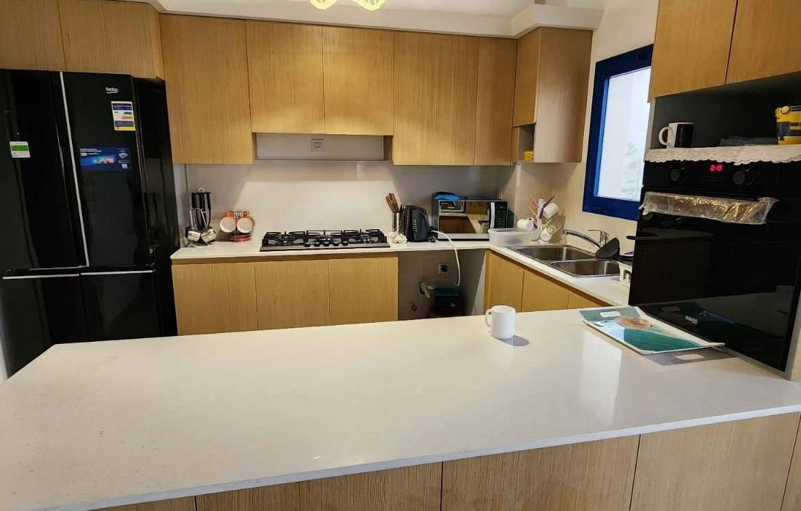 Kitchen with white island and black fridge - townhouse in Marassi, North Coast