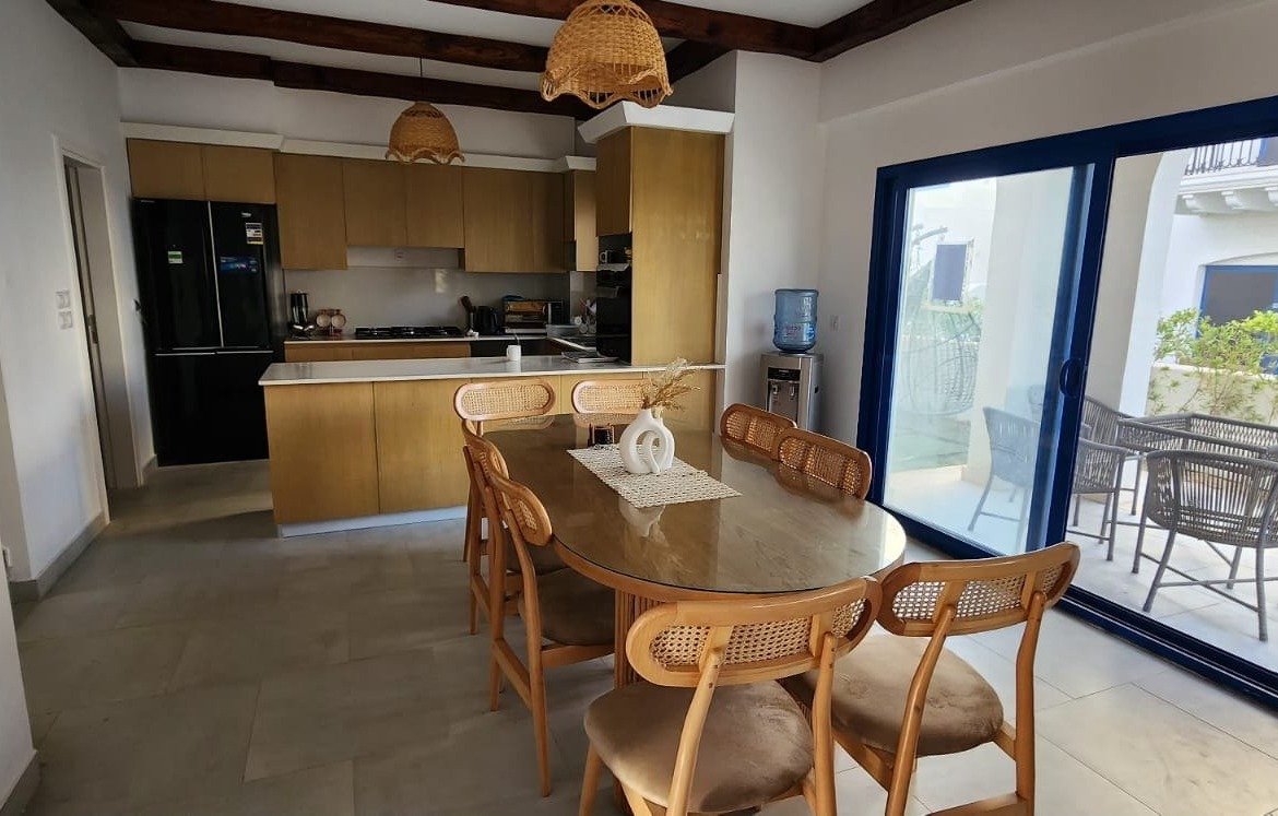Dining table with wooden chairs and open kitchen - townhouse in Marassi, North Coast
