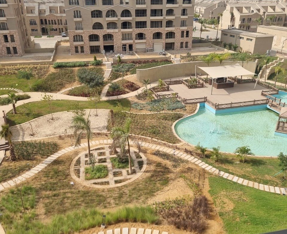 Balcony view over a pool and gardens with apartment buildings beyond - apartment in Green Square, Mostaqbal City
