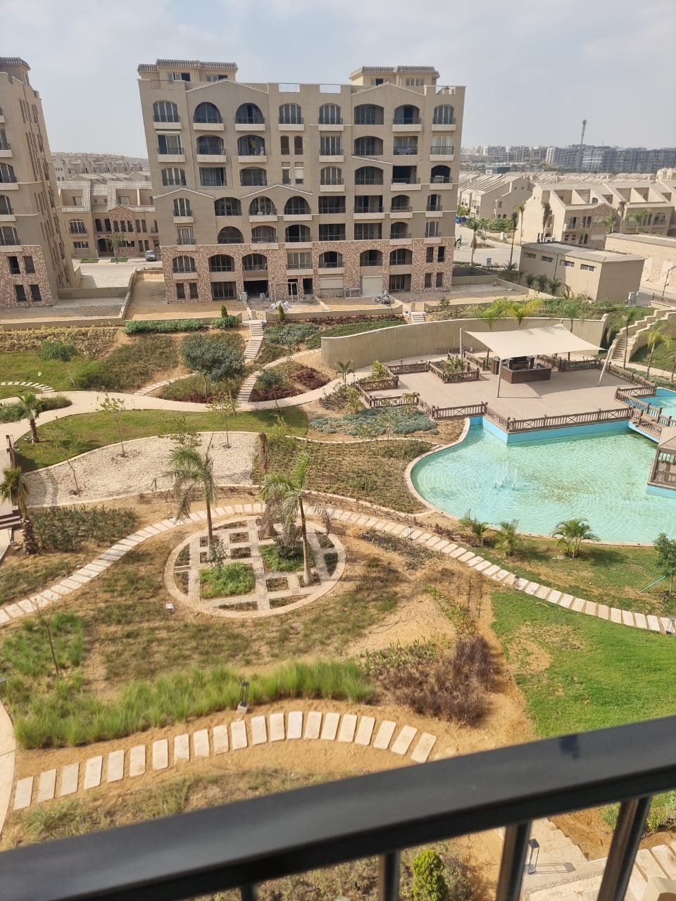 Balcony view over a pool and gardens with apartment buildings beyond - apartment in Green Square, Mostaqbal City