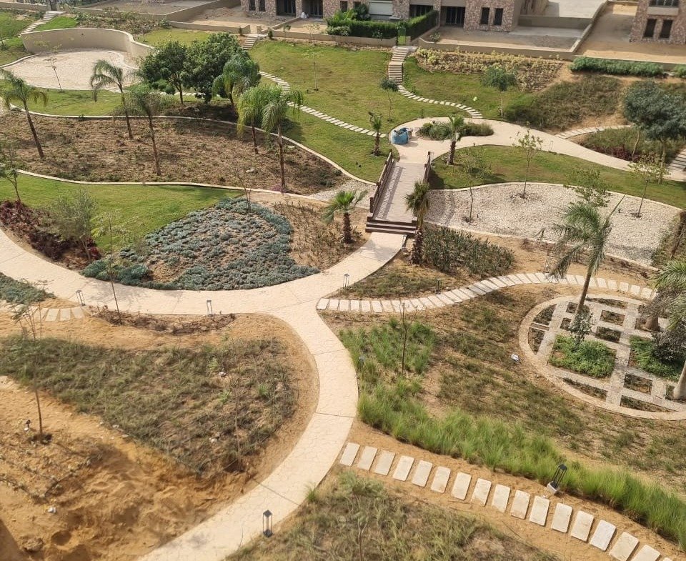 Garden with curved sand-coloured paths seen from a balcony - apartment in Green Square, Mostaqbal City