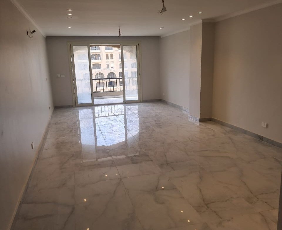 Empty living room with a polished marble floor and a balcony door - apartment in Green Square, Mostaqbal City