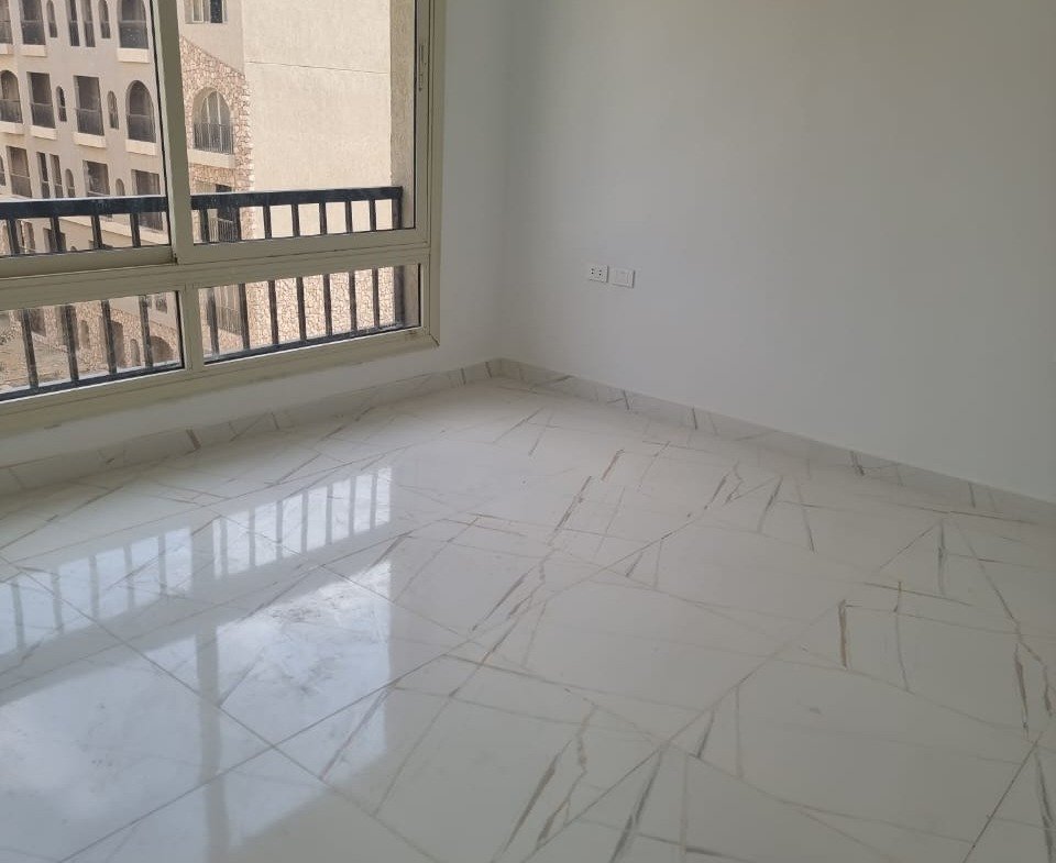 Bright empty bedroom with a balcony window and a marble floor - apartment in Green Square, Mostaqbal City