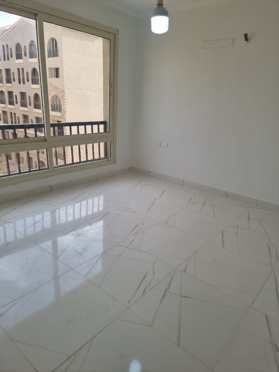 Bright empty bedroom with a balcony window and a marble floor - apartment in Green Square, Mostaqbal City