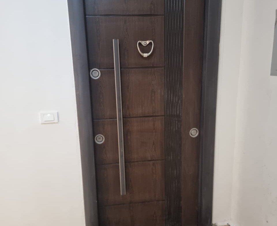 Apartment entrance with a dark wooden door and a marble threshold - apartment in Green Square, Mostaqbal City