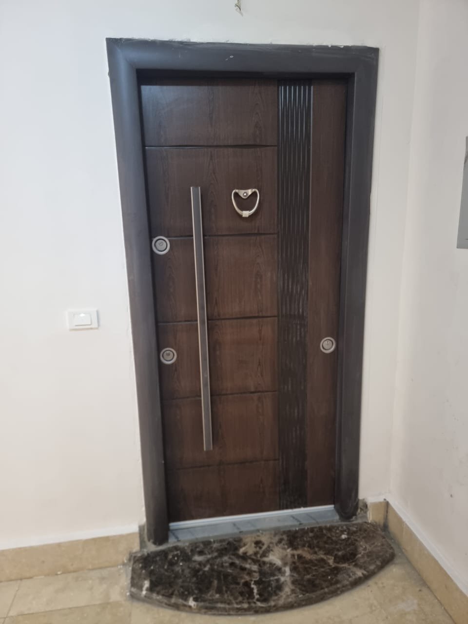 Apartment entrance with a dark wooden door and a marble threshold - apartment in Green Square, Mostaqbal City