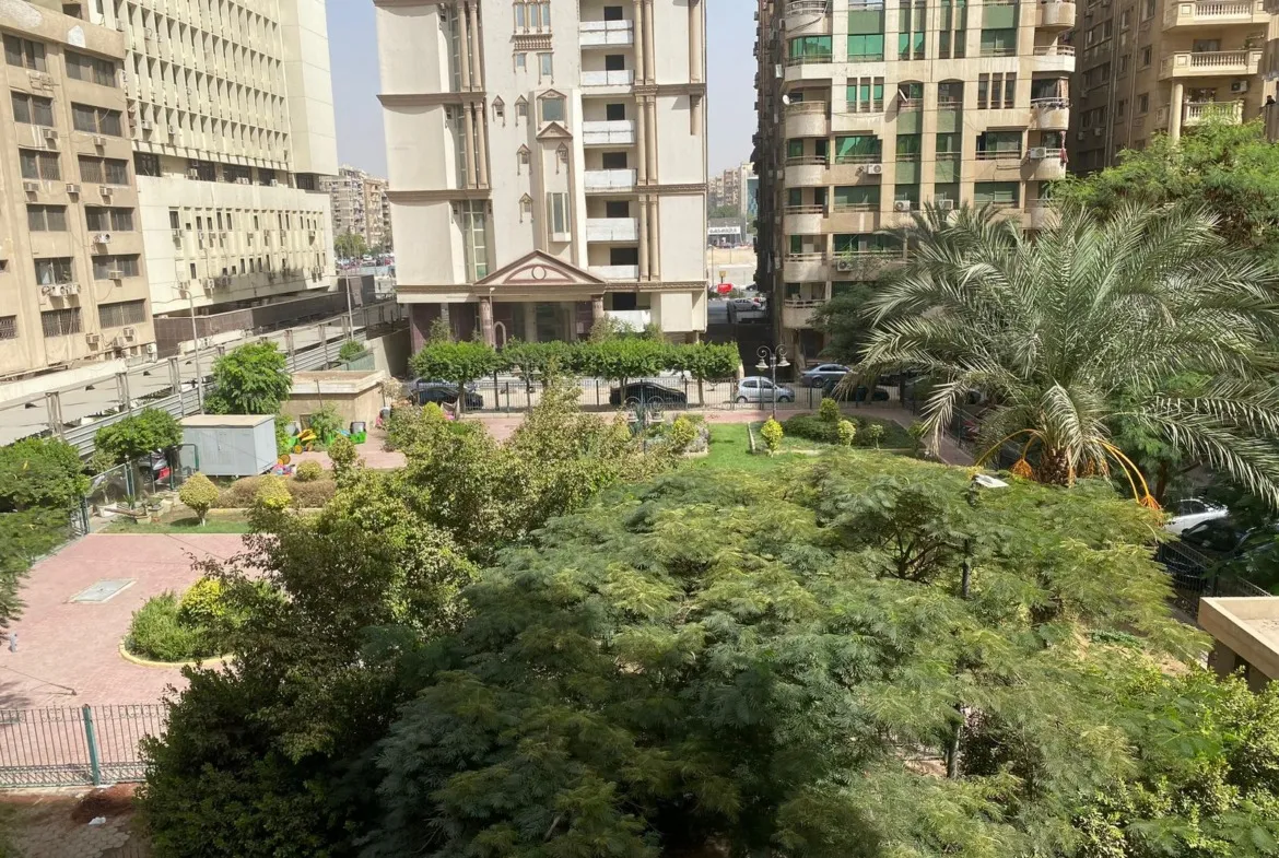 Green garden with tall residential buildings behind - apartment in Heliopolis