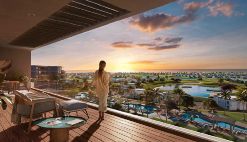 Woman on a balcony watching sunset over the resort lagoon - chalet in Hacienda Waters, North Coast