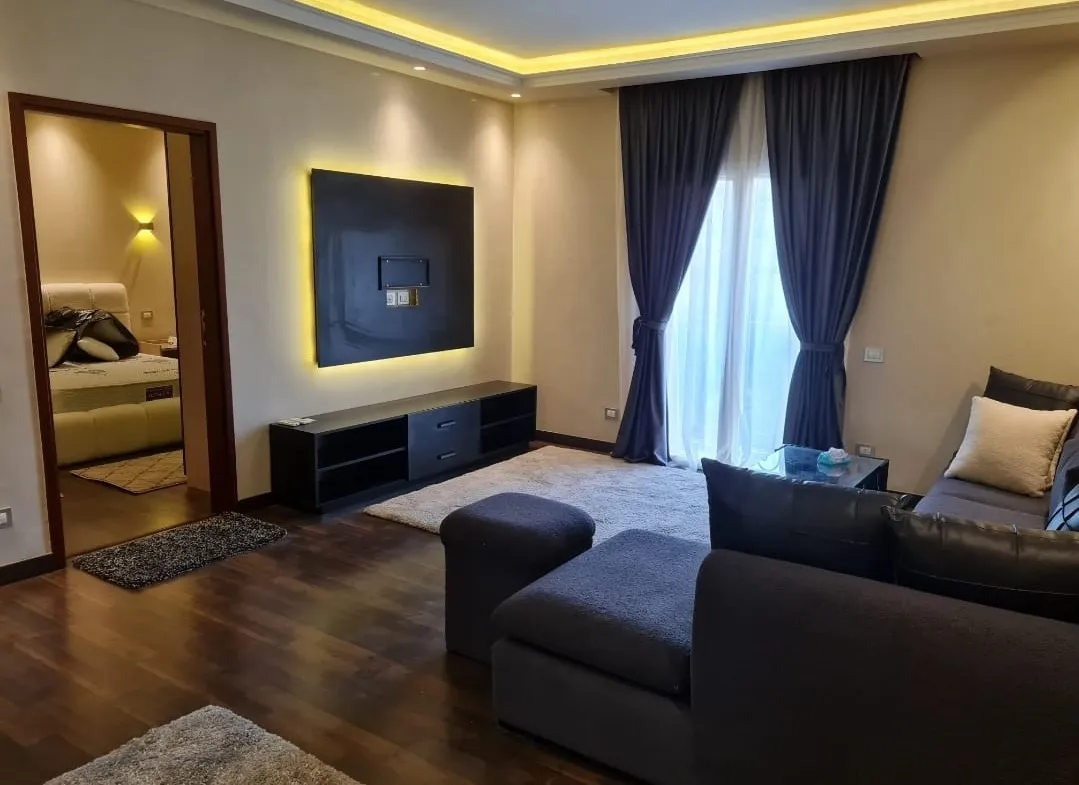 Living room with dark sofa and television - studio in Hyde Park, New Cairo