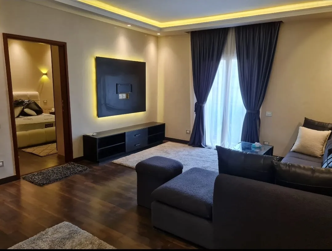 Living room with dark sofa and television - studio in Hyde Park, New Cairo