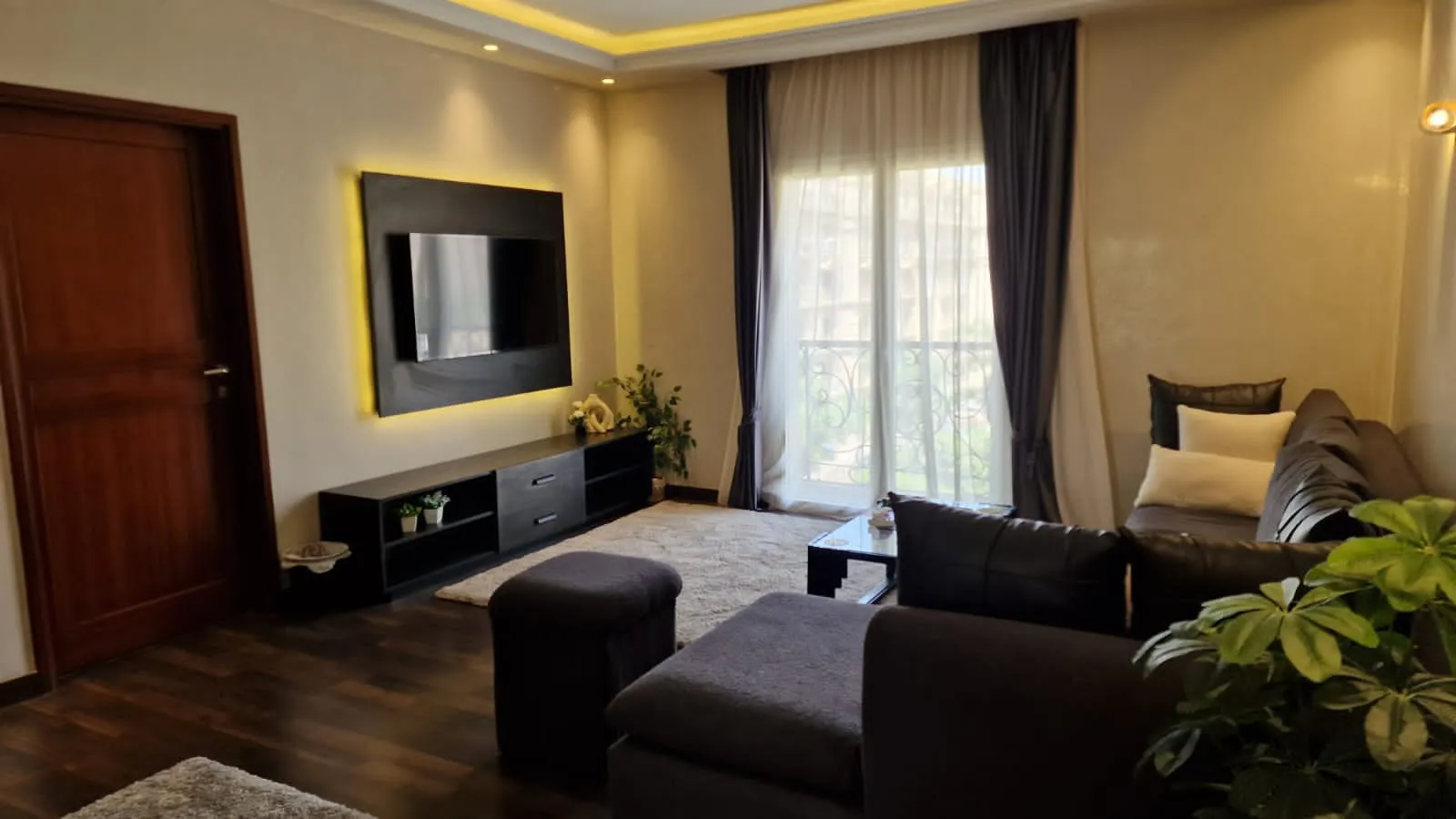 Television wall and curtained balcony door - studio in Hyde Park, New Cairo