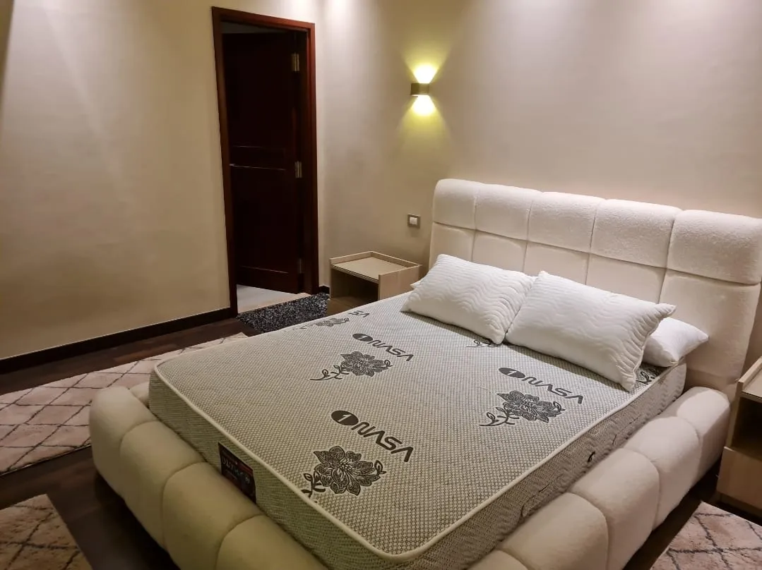 Bedroom with white upholstered bed - studio in Hyde Park, New Cairo
