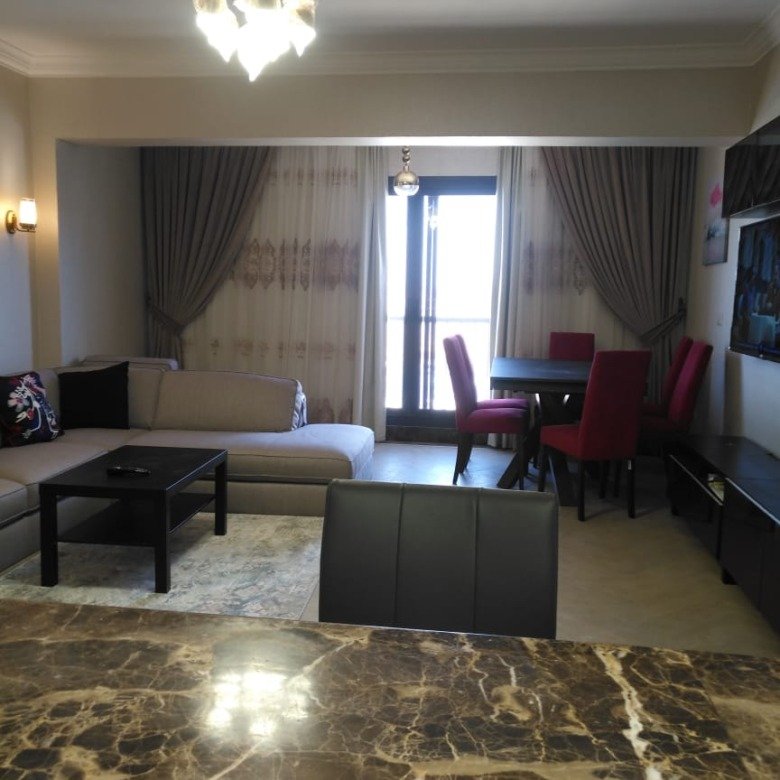 Reception with a brown marble floor and a dining set in the background - duplex in Porto, New Cairo