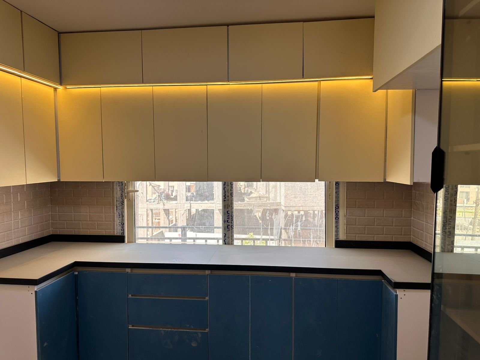 Kitchen 2 – Lake Park مطبخ بدواليب سفلية زرقاء وعلوية بيضاء وإضاءة تحتها - شقة في ليك بارك تاج سيتي