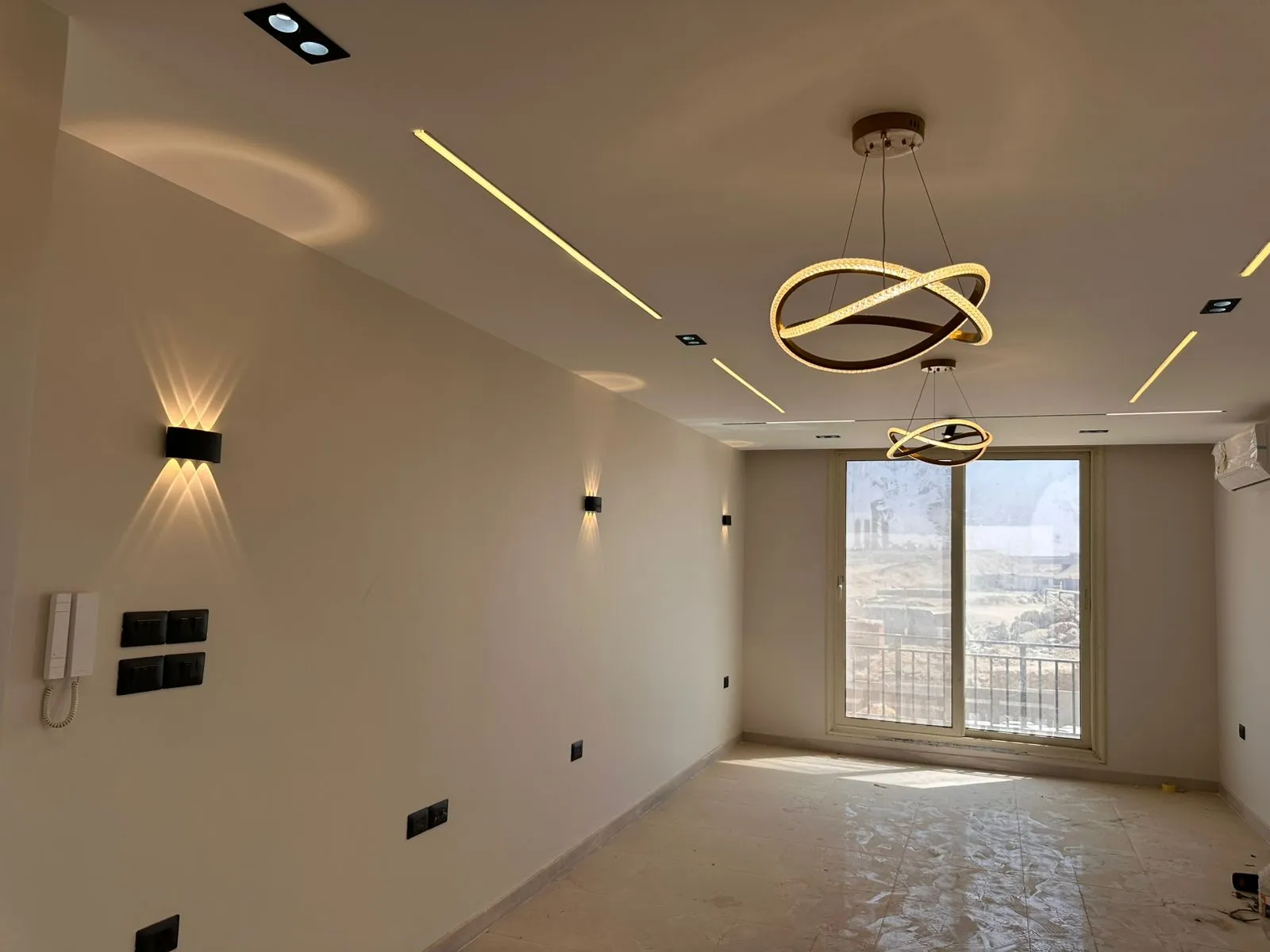 Reception – Lake Park Taj City غرفة معيشة جديدة بخطوط إضاءة سقف ونجفة تعليق وباب بلكونة - شقة في ليك بارك تاج سيتي