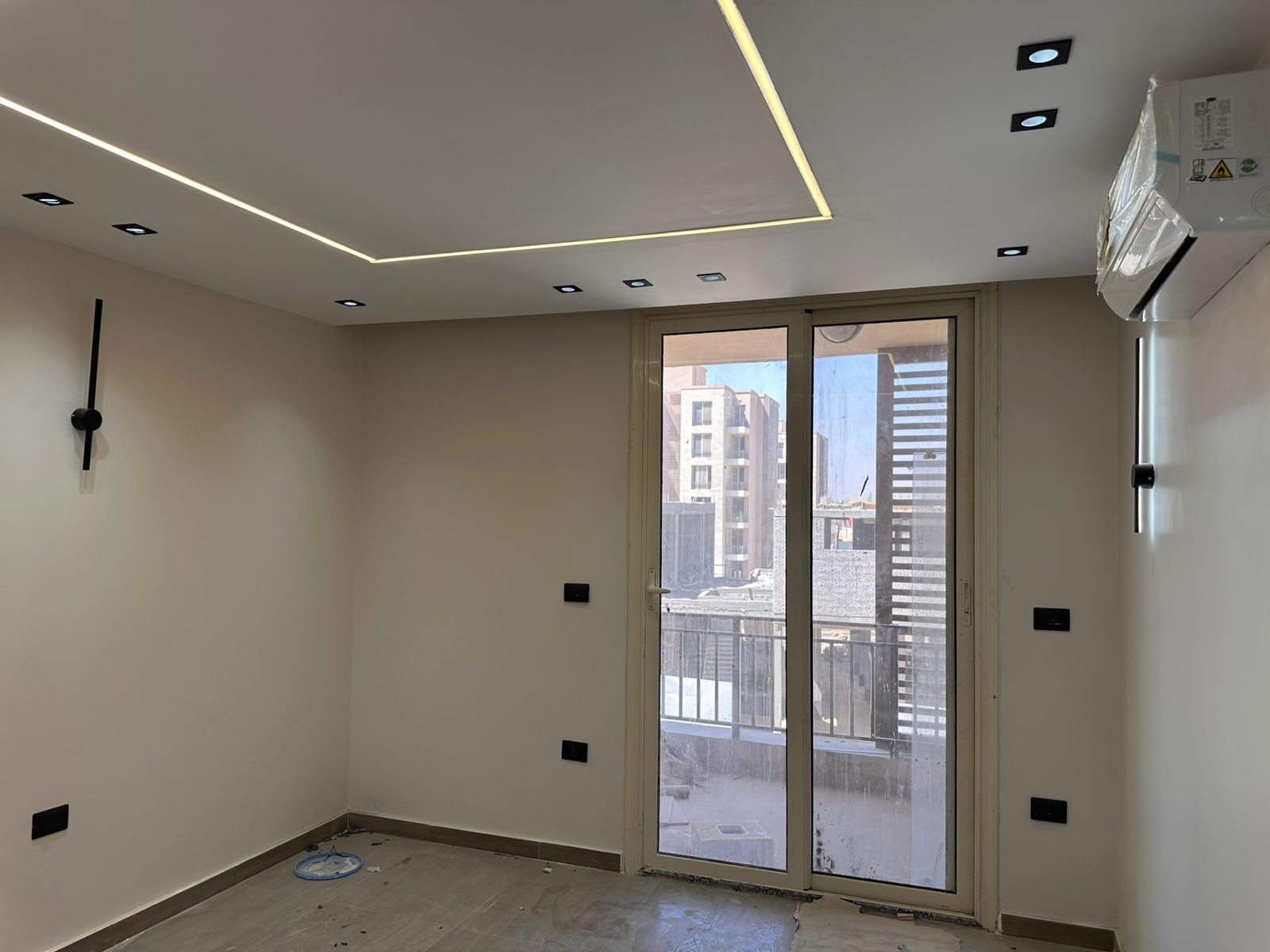 Room 2 – Lake Park غرفة بتكييف حائط وباب بلكونة يطل على عمارات - شقة في ليك بارك تاج سيتي