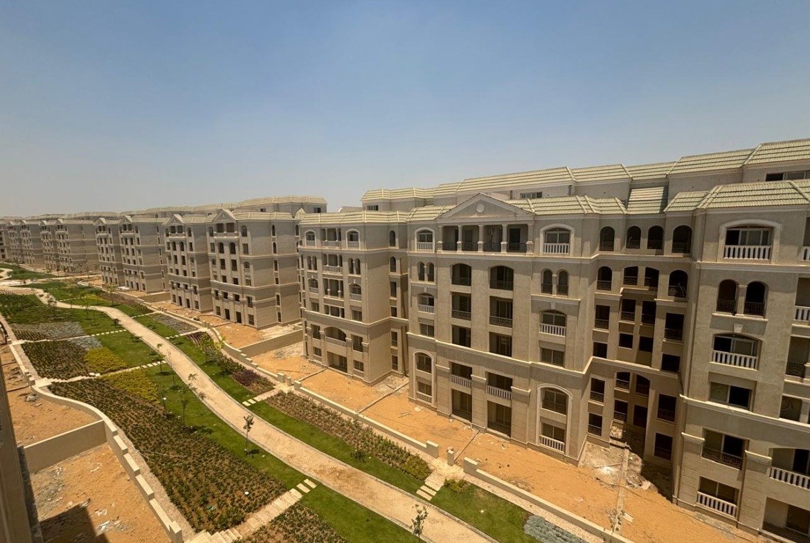 Long row of apartment blocks with planted slopes and a paved walkway - apartment in L’avenir Sabbour, Mostaqbal City